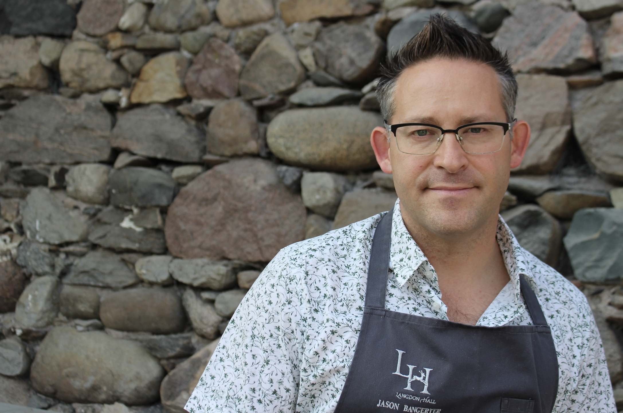 Chef Jason Bangerter posing against a stone wall