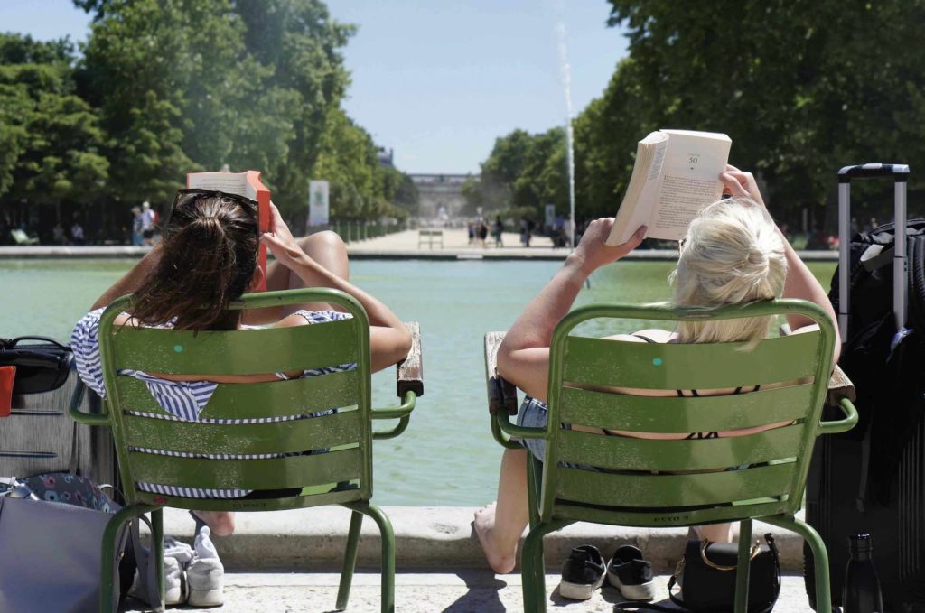 Women relaxing outside in chairs in park while enjoying the top things to do in Paris for book lovers